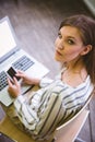 Portrait of confident businesswoman using cellphone over laptop at office Royalty Free Stock Photo