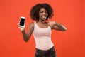 Portrait of a confident casual afro girl showing blank screen mobile phone isolated over red background Royalty Free Stock Photo