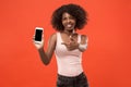 Portrait of a confident casual afro girl showing blank screen mobile phone isolated over red background Royalty Free Stock Photo
