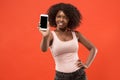 Portrait of a confident casual afro girl showing blank screen mobile phone isolated over red background Royalty Free Stock Photo