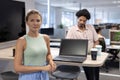 Portrait of confident cauasian businesswoman standing by laptop against biracial businesswoman