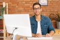 Portrait of confident cheerful handsome young freelance designer male in stylish glasses working on desktop computer Royalty Free Stock Photo