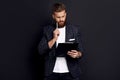 Portrait of confident concentrated self-assured handsome bearded guy writing information to the documents on clipboard in hid