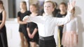 Portrait of confident cute Caucasian boy waltzing in slow motion winking at camera. Little ballet dancer rehearsing