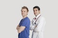 Portrait of a confident doctor and male nurse standing with arms crossed over gray background Royalty Free Stock Photo