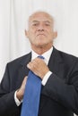 Portrait of confident elderly businessman adjusting his necktie Royalty Free Stock Photo