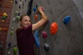 Portrait of confident female athlete climbing wall in gym Royalty Free Stock Photo