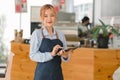 Portrait of confident female barista standing at counter. Woman cafe owner in apron looking at camera and smiling while Royalty Free Stock Photo