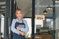 Portrait of confident female barista standing at counter. Woman cafe owner in apron looking at camera and smiling while Royalty Free Stock Photo