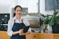 Portrait of confident female barista standing at counter. Woman cafe owner in apron looking at camera and smiling while Royalty Free Stock Photo