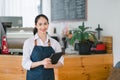 Portrait of confident female barista standing at counter. Woman cafe owner in apron looking at camera and smiling while Royalty Free Stock Photo