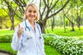 Portrait of a confident female doctor showing thumbs up in garden outdoor Royalty Free Stock Photo