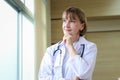 Portrait of confident female doctor in workwear with stethoscope thinking and taking decisions with hand on chin, looking through