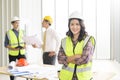 Portrait of confident female engineer standing on frontage while colleagues discussing and meeting on background Royalty Free Stock Photo