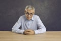 Portrait of confident friendly senior man sitting at table and smiling looking at camera. Royalty Free Stock Photo