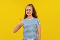 Portrait of confident good-looking young brunette woman in striped t shirt, smiling and showing thumb-up. Indoor studio shot on Royalty Free Stock Photo