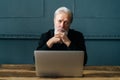Portrait of confident gray-haired mature business man sitting at wooden table with laptop computer at home office Royalty Free Stock Photo
