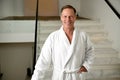 Portrait of a confident handsome middle aged man wearing terry bathrobe and smiling toothy smile looking at camera standing on the Royalty Free Stock Photo