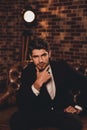 Portrait of confident harsh man in black suit sitting on sofa