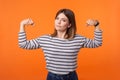 Portrait of confident independent young woman with brown hair in long sleeve striped shirt. indoor studio shot isolated on orange