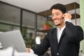 Portrait of confident latin man in wireless headset using laptop computer sitting in contemporary office space, male Royalty Free Stock Photo