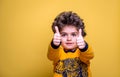 Portrait of confident little boy giving you thumbs up isolated on yellow background. Smart five years old child. Back to