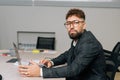 Portrait of confident male boss wearing stylish suit and eyeglasses working on laptop computer sitting at office desk Royalty Free Stock Photo