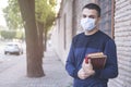 Portrait of confident male student holding books while standing in university campus with pandemics mask Royalty Free Stock Photo