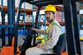 Male worker sitting in forklift and looking at camera in warehouse Royalty Free Stock Photo