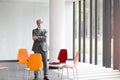 Portrait of confident mature businessman standing with arms crossed amidst chairs in new office Royalty Free Stock Photo