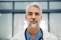 Portrait of confident mature doctor standing in Hospital corridor. Handsome doctor with gray hair wearing white coat Royalty Free Stock Photo