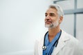 Portrait of confident mature doctor standing in Hospital corridor. Handsome doctor with gray hair wearing white coat Royalty Free Stock Photo