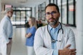 Portrait of confident mature doctor standing in Hospital corridor. Handsome doctor wearing white coat, stethoscope Royalty Free Stock Photo