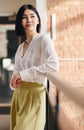 Portrait of confident mid adult Chinese businesswoman leaning on railing and looking away with a serene expression