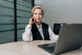 Portrait of confident middle-aged businesswoman, company executive, CEO sitting at desk with laptop, looking at camera Royalty Free Stock Photo