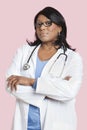 Portrait of confident mixed race female surgeon over pink background