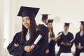 Portrait of Asian female student in a university graduate gown and with a diploma in her hands.