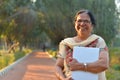 Portrait of a confident retired Senior Indian woman carrying a laptop in a park wearing off white salwar kamiz. Concept - Digital Royalty Free Stock Photo