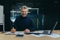 Portrait of a confident senior man businessman, accountant, manager sitting in the office at the table, smiling and Royalty Free Stock Photo