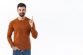 Portrait of confident smart, bearded man pointing finger up, showing way to advertisement, smiling, inviting to check