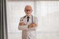 Portrait of confident smiling elderly doctor standing with arms crossed Royalty Free Stock Photo