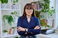 Portrait of confident smiling middle-aged woman with crossed arms at home Royalty Free Stock Photo