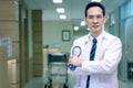 Portrait of confident smiling senior Asian male doctor in white workwear holding stethoscope and looking at camera, standing with Royalty Free Stock Photo