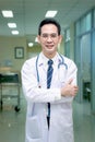 Portrait of confident smiling senior Asian male doctor in white workwear holding stethoscope and looking at camera, standing with Royalty Free Stock Photo