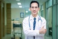 Portrait of confident smiling senior Asian male doctor in white workwear holding stethoscope and looking at camera, standing with Royalty Free Stock Photo