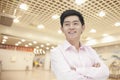 Portrait of confident smiling young businessman in button down shirt with arms crossed, indoors