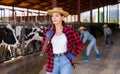 Smiling young woman cow breeder standing in cowshed Royalty Free Stock Photo