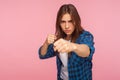 Portrait of confident strong girl in checkered shirt standing with clenched fists in defensive pose, ready to punch Royalty Free Stock Photo