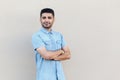 Portrait of confident successful handsome young bearded businessman in blue shirt standing, crossed arms and looking at camera Royalty Free Stock Photo