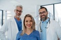 Portrait of confident three doctors standing in Hospital corridor. Medical team wearing white coat, stethoscope around Royalty Free Stock Photo